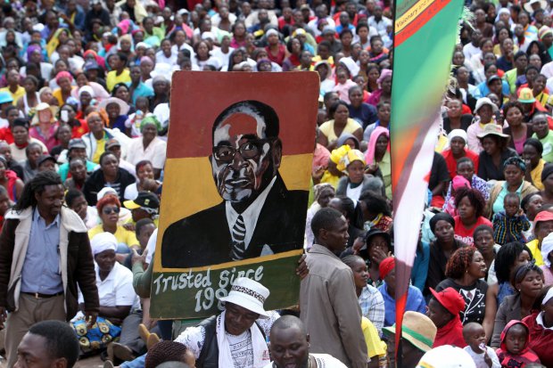 FILE - In Wednesday, July 20, 2016 file photo, thousands of Mugabe supporters carry his portrait while gathering at the party headquarters in Harare. Veterans of Zimbabwe's independence war made a significant break with President Robert Mugabe for the first time Thursday, July 21, 2016, calling him dictatorial, manipulative and egocentric. (AP Photo/Tsvangirayi Mukwazhi, File)